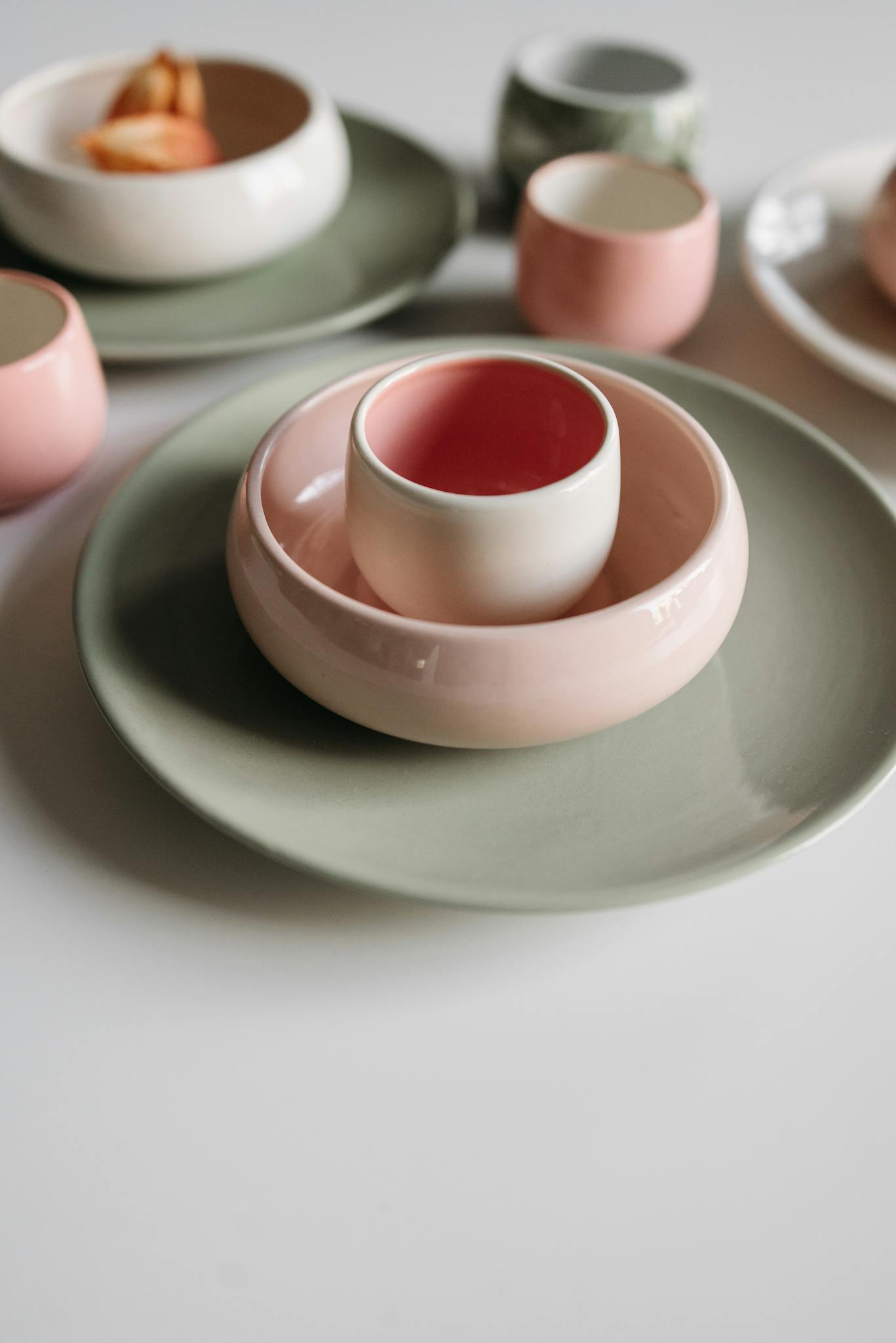 A minimalist arrangement of pastel ceramic dishware including bowls and plates.