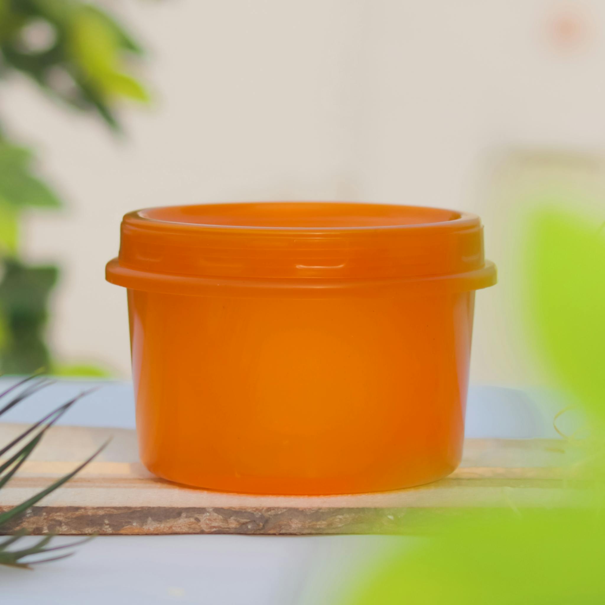 Bright orange plastic container with a lid on wooden board, perfect for storage solutions.