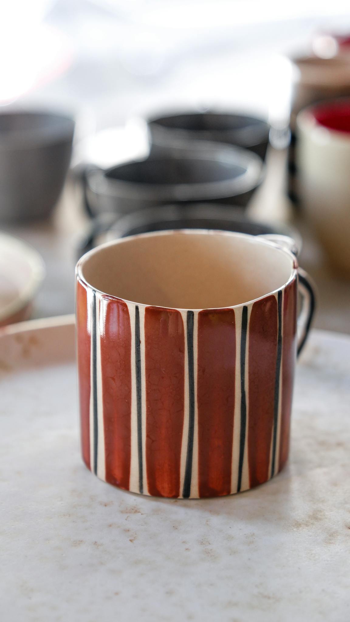Unique striped ceramic mug in natural lighting, great for kitchen decor.